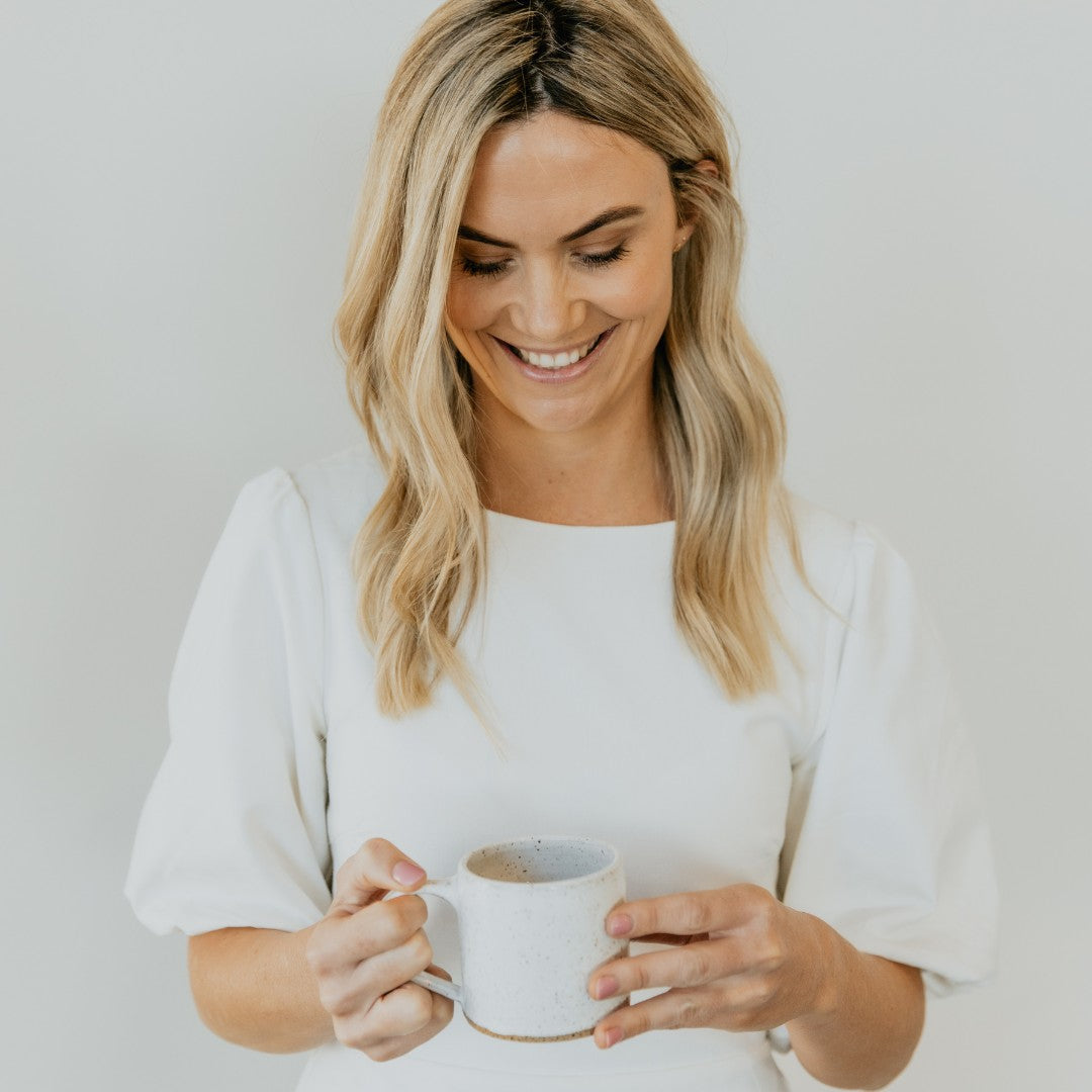 Woman in white dress holding a mug of coffee | Adashiko Collagen | 100% Natural Skincare