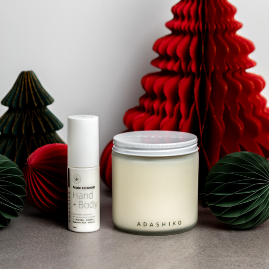 Light + Luxe Due - Adashiko Christmas Candle Jar next to Triple Ceramide Hand + Body bottle on a table with  Christmas decorations | Adashiko Collagen | 100% Natural Skincare